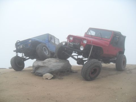 1990 Ford Bronco - Two modified Jeeps, a red Wrangler and a blue Cherokee, navigate a rocky obstacle course.