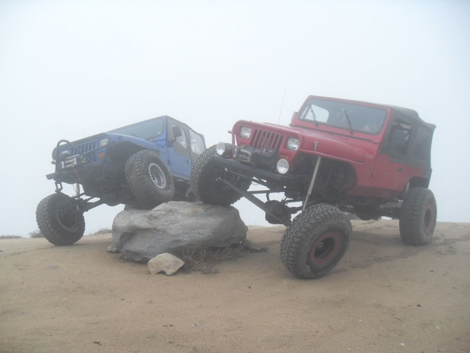 Red Jeep Wrangler and blue Jeep Cherokee on rocks