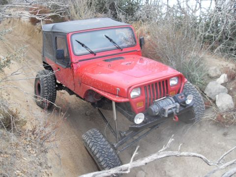 1990 Ford Bronco - Modified Jeep Wrangler tackling an off-road trail with steep inclines and loose dirt.