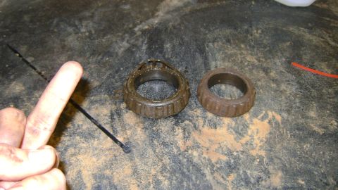 1986 Ford Bronco - Used wheel bearings shown on a dirty surface, with one bearing exhibiting cage damage.