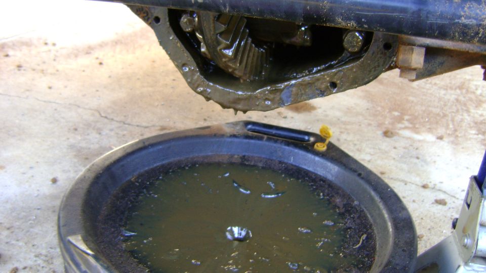 Differential housing with gears and draining oil into a black pan