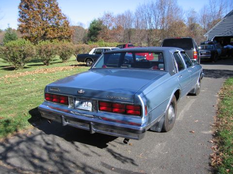 2001 Ford Crown Victoria - A light blue Chevrolet Caprice Classic is parked on a driveway with other vehicles visible.
