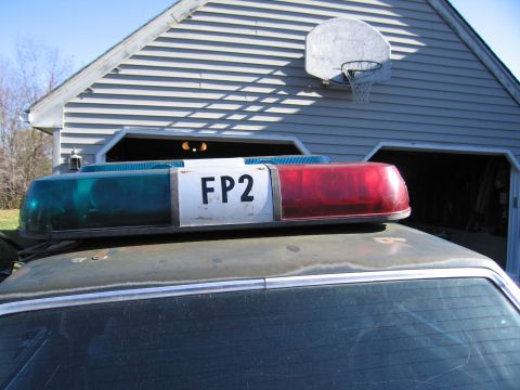 2001 Ford Crown Victoria - A close-up view of a police light bar with "FP2" marking, situated on a vehicle's roof.