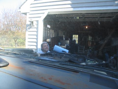 2001 Ford Crown Victoria - A man smiles as he looks out from inside a vehicle towards a messy garage.