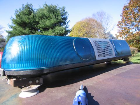 2001 Ford Crown Victoria - A blue emergency light bar, likely for a police or fire vehicle, is shown mounted on a surface. The light bar features ribbed blue lenses a…