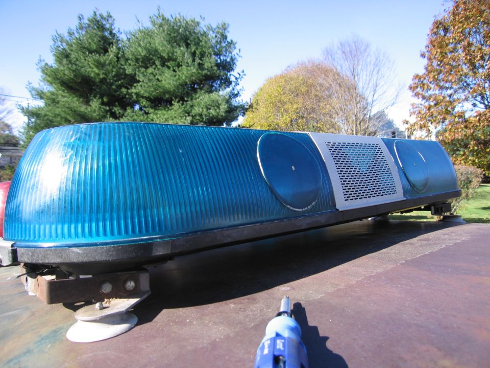 Blue emergency light bar with silver grille and circular lenses