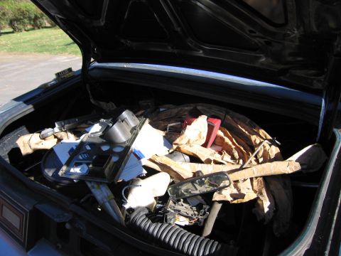 2001 Ford Crown Victoria - The trunk of a car is filled with assorted automotive parts and packing materials.