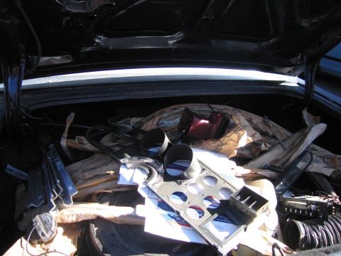 2001 Ford Crown Victoria - The interior of a car trunk is packed with assorted automotive parts and protective wrapping.