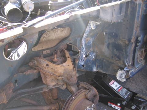 2001 Ford Crown Victoria - Close-up view of a heavily rusted vehicle chassis and suspension system, with a jack visible.