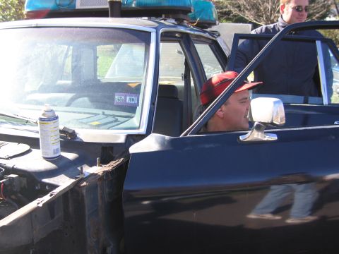 2001 Ford Crown Victoria - Interior view of a 2001 Ford Crown Victoria police car, showing the driver and a visible inspection sticker on the windshield.
