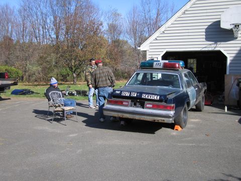 2001 Ford Crown Victoria - A dark-colored sedan, possibly a former police vehicle, is parked in a driveway with "OUT OF SERVICE" visible on its rear.