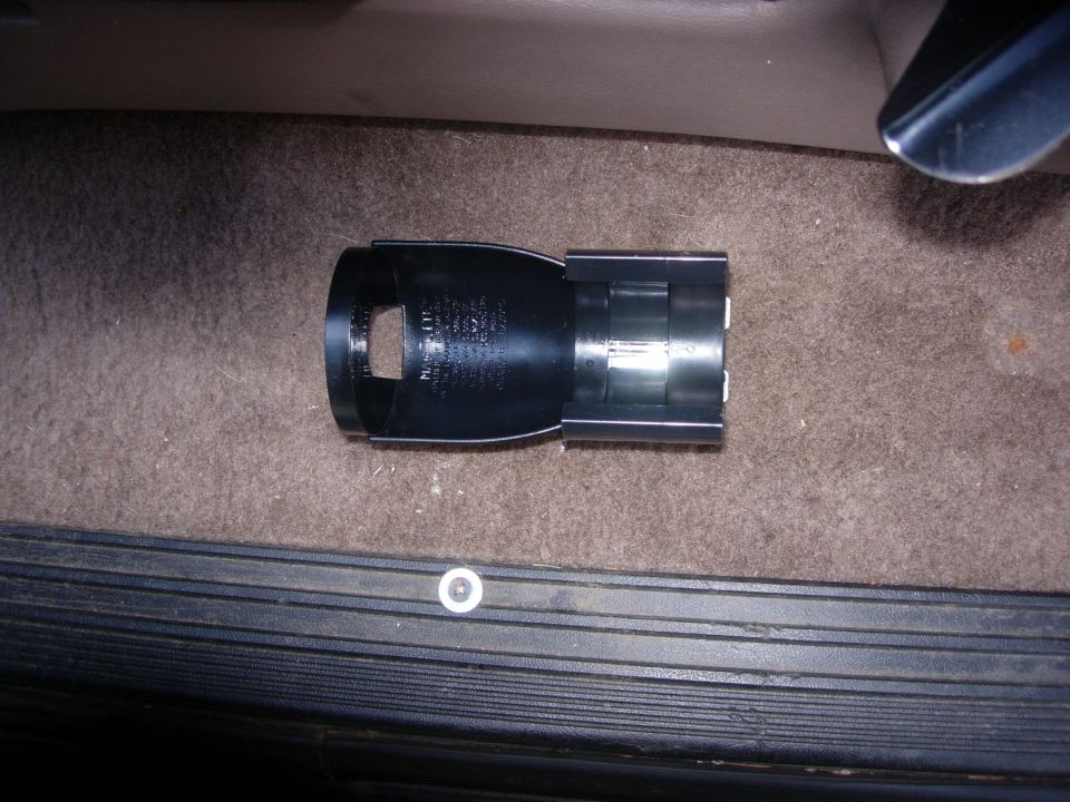 Black plastic interior car part with text on carpet next to door sill