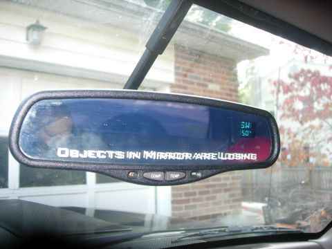 1993 Ford Bronco - The interior rearview mirror displays the classic warning text, along with a digital readout for temperature and compass direction.