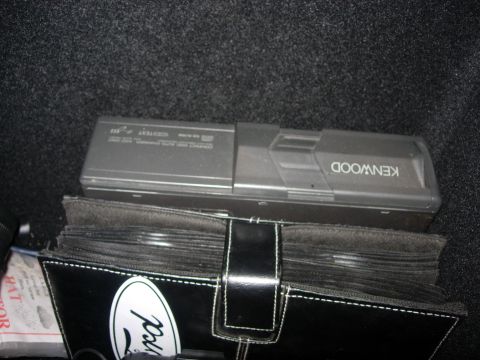 1993 Ford Bronco - A Kenwood CD changer sits atop a CD case with a Ford emblem, likely in a vehicle's trunk.