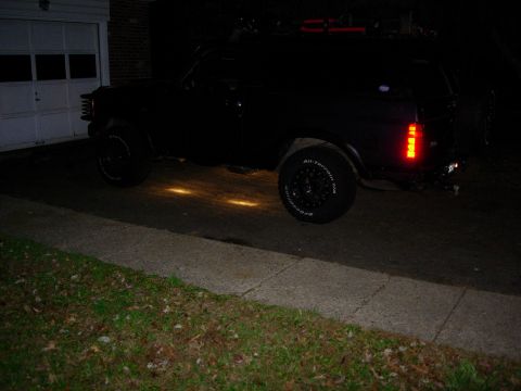 1993 Ford Bronco - 1993 Ford Bronco parked in driveway at night, showing side profile and rear tail lights.