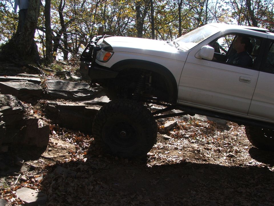 White off-road SUV with large tires navigating rocky terrain