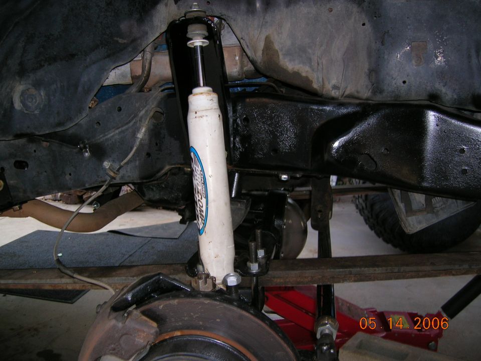 Underside front suspension with white shock absorber, brake rotor and black frame rail