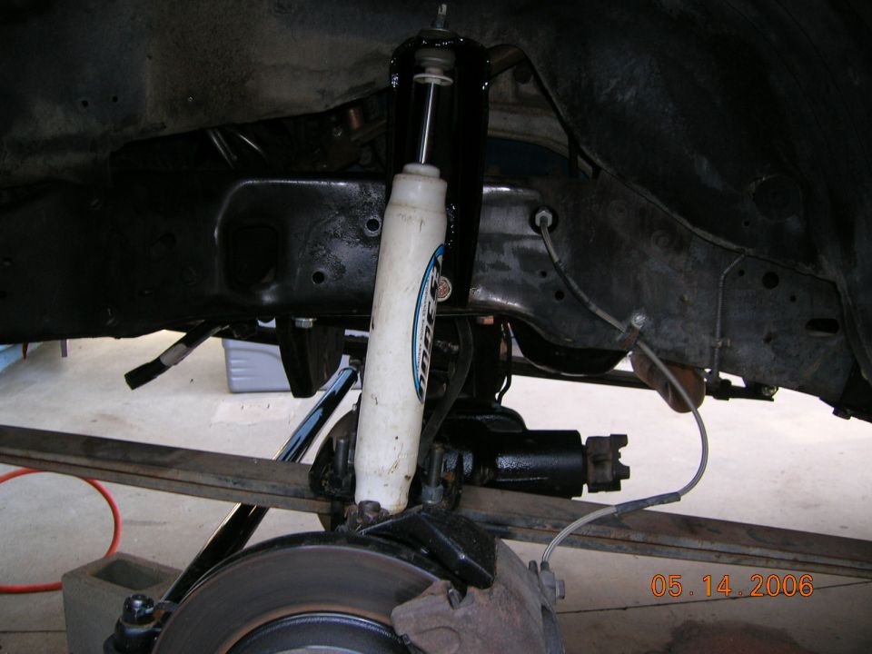 Front axle underside with white shock, black radius arm and brake rotor on a lifted truck