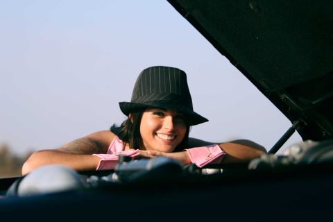 2003 Mercury Marauder - A woman wearing a fedora and pink top smiles while leaning on the engine of a car.