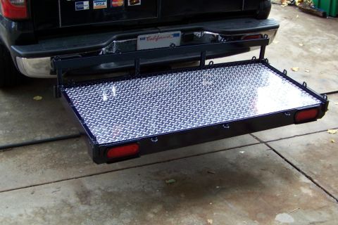 1994 Ford F-150 - The rear of a black pickup truck is shown with a diamond plate cargo carrier extended.