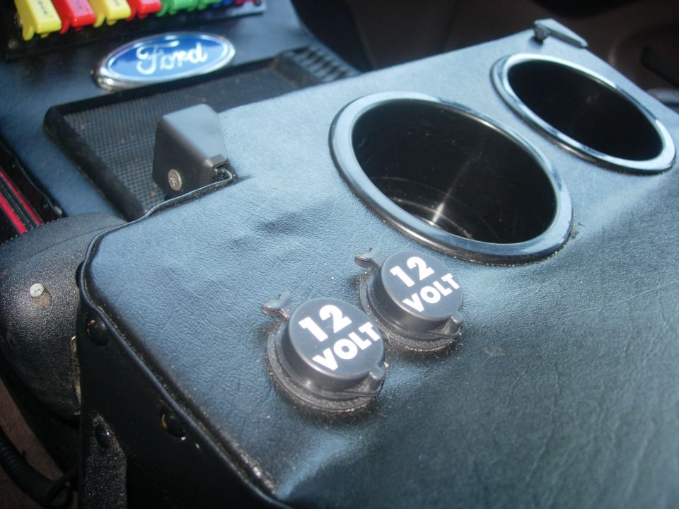 Interior center console of a Ford Bronco with 12-volt outlets and cup holders.