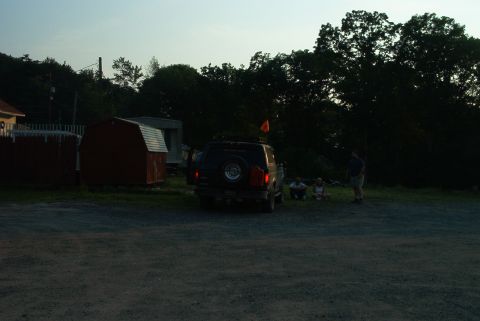 1993 Ford Bronco - A 1993 Ford Bronco is parked in a gravel lot near some sheds as people gather in the background.