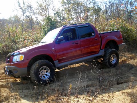 2002 Ford Sport Trac - This red 2002 Ford Sport Trac is shown navigating a dirt trail, likely during an off-roading excursion.
