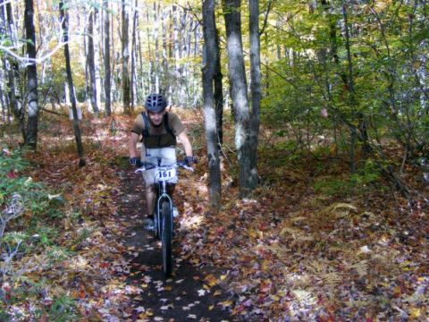 1972 Ford Ranchero - A mountain biker navigates a wooded trail during a race, indicated by the number 161 on their handlebars.