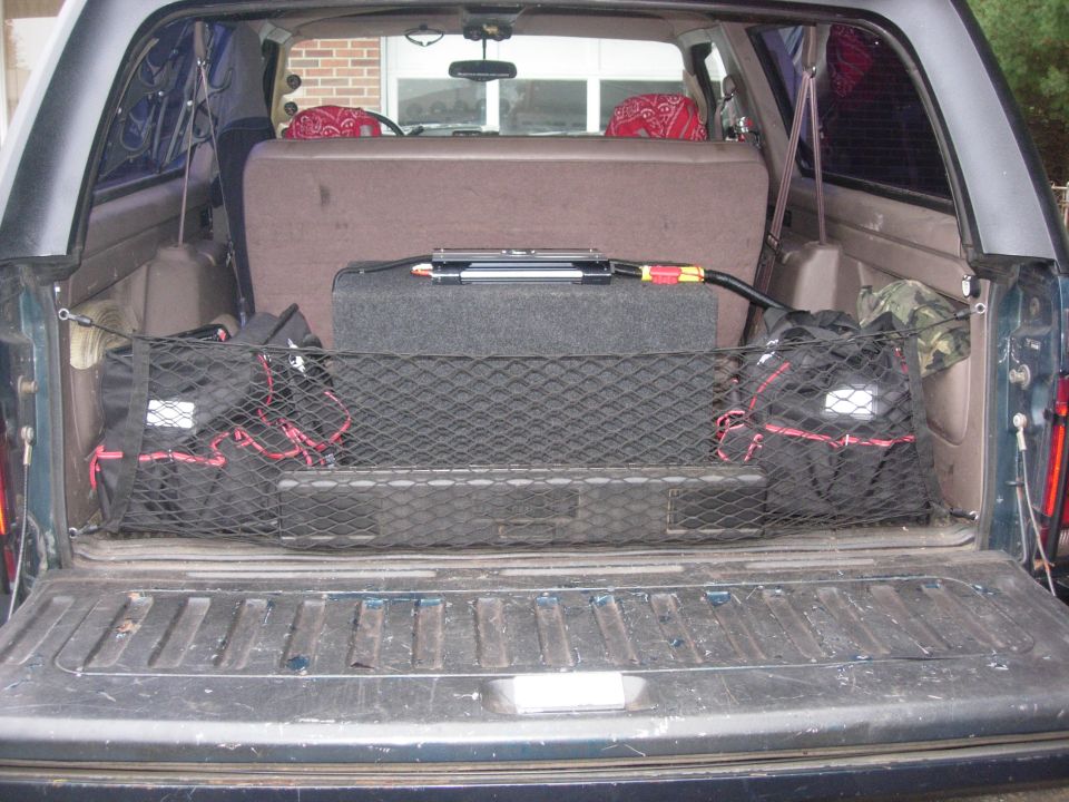 Interior cargo area with subwoofer and storage bags secured by a net
