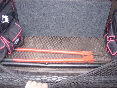 1993 Ford Bronco - Tools are stored in the cargo area of a vehicle, with a mesh net securing the items.
