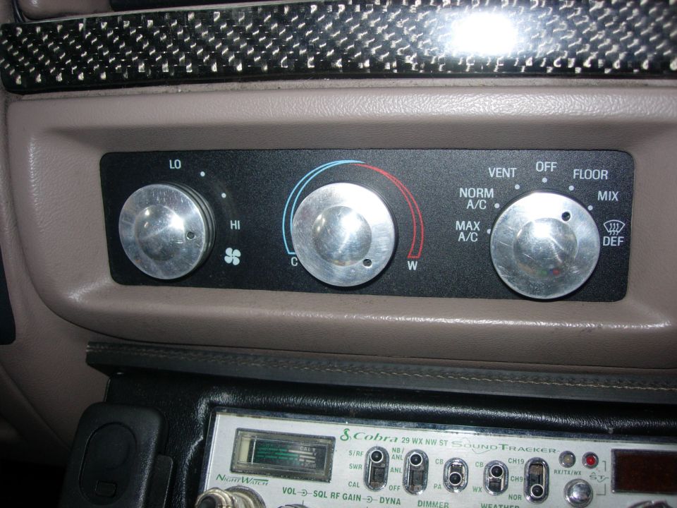 Interior view of climate controls with knobs for fan speed, temperature, and mode, above a Cobra CB radio