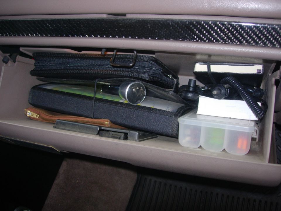 Glove compartment filled with bags, a small container of fuses, and other items