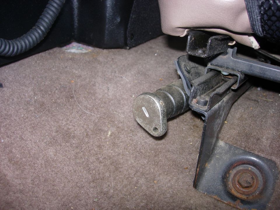 Close-up of a seat adjustment lever mechanism on the floor of a vehicle