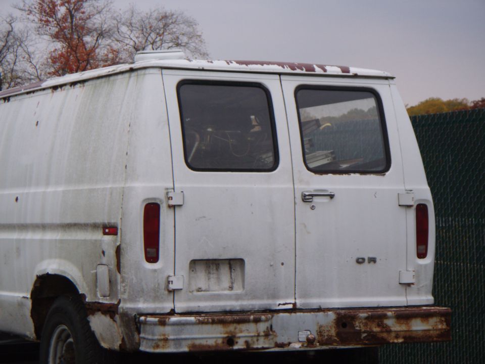 Rear view of a white van with rust and dirt