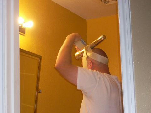 1992 Ford Bronco - A man is seen in a bathroom, holding a pipe and applying tape to his head.