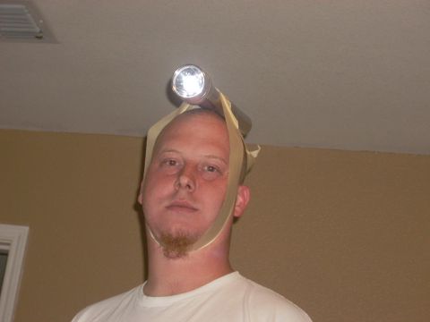 1992 Ford Bronco - A man with a goatee wears a flashlight on his head, secured by tape and straps.