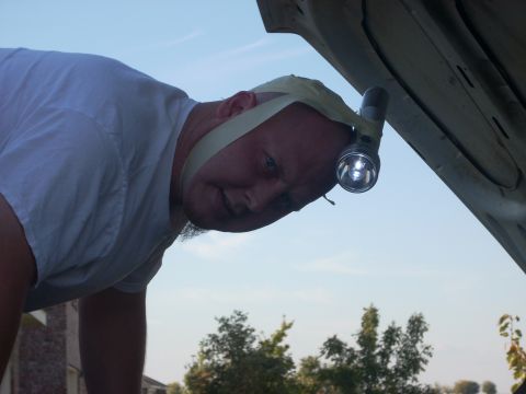 1992 Ford Bronco - Man uses a makeshift headlamp to work on a vehicle's engine bay.