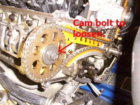2007 Ford Mustang - This image shows a close-up view of an engine's timing chain and sprockets, with text indicating a cam bolt to loosen.