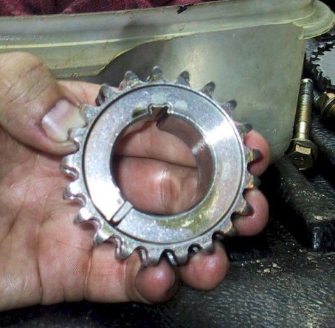 2007 Ford Mustang - A person holds a metal pulley with teeth and a keyway slot, likely a car part.