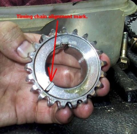 2007 Ford Mustang - A close-up shows a timing chain gear with an alignment mark indicated by a red arrow.