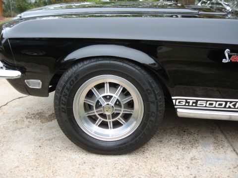 1968 Shelby GT500 - The side profile of a black car shows a G.T.500KR decal and a distinctive wheel design.