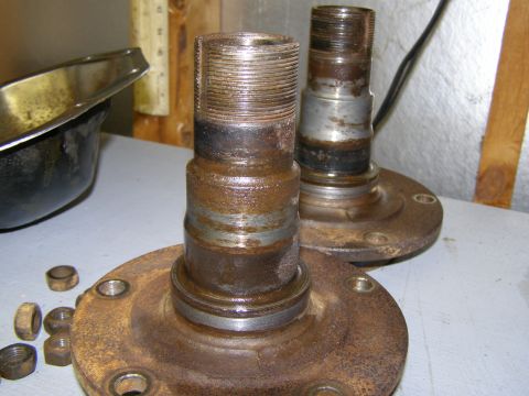 1993 Ford Bronco - Two heavily rusted wheel hubs and several nuts are displayed on a workbench, suggesting a repair or parts inventory.