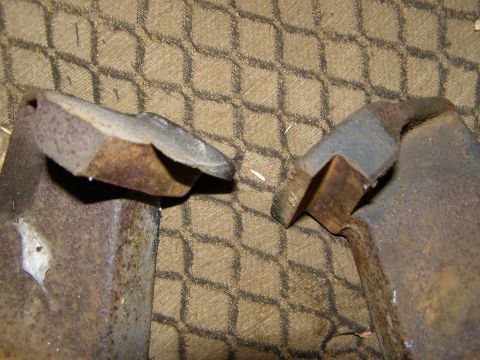 1993 Ford Bronco - Close-up of two rusty metal brackets against a textured fabric background.