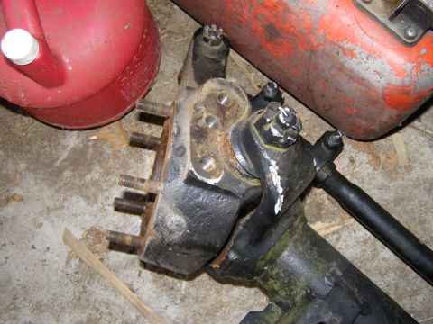 1993 Ford Bronco - A vehicle axle assembly with multiple studs and steering components is shown in a cluttered setting.