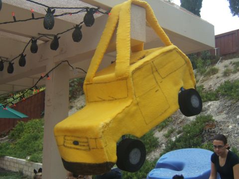 1988 Ford Bronco - A handmade yellow toy truck, possibly a piñata, hangs outdoors.