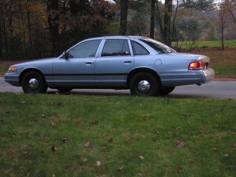 1991 Ford LTD Crown Victoria - Side profile of a 1991 Ford Crown Victoria LTD parked on the side of a road with trees in the background.