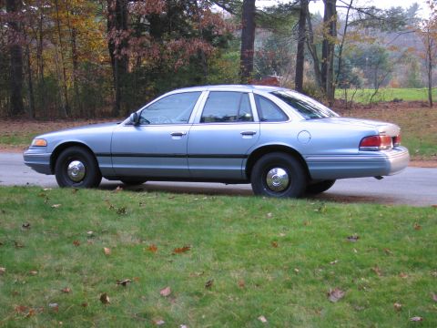 1991 Ford LTD Crown Victoria - A light blue 1991 Ford Crown Victoria LTD is parked on the side of the road with fall foliage in the background.