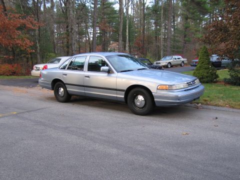1991 Ford LTD Crown Victoria - Silver sedan parked on a street with trees and other vehicles visible in the background.