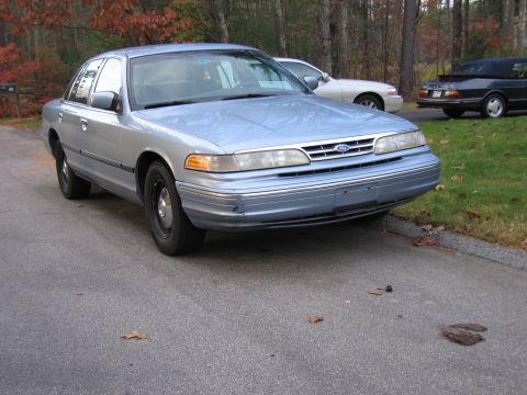 1991 Ford LTD Crown Victoria - A light blue 1991 Ford Crown Victoria is parked on the side of the road with autumn leaves on the ground.