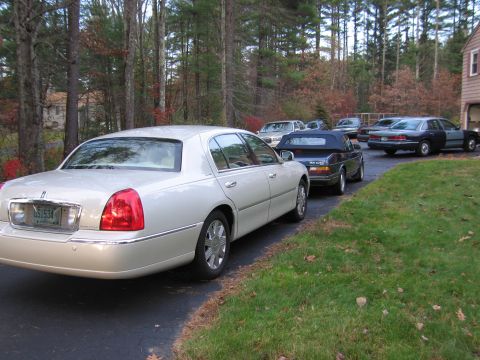 1991 Ford LTD Crown Victoria - Several cars are parked in a driveway on a fall day, with a white Lincoln Town Car in the foreground.